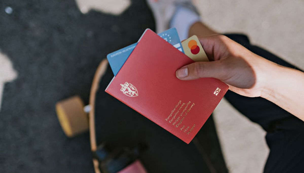 Hånd som holder pass, mastercard og trygdehelsekort
