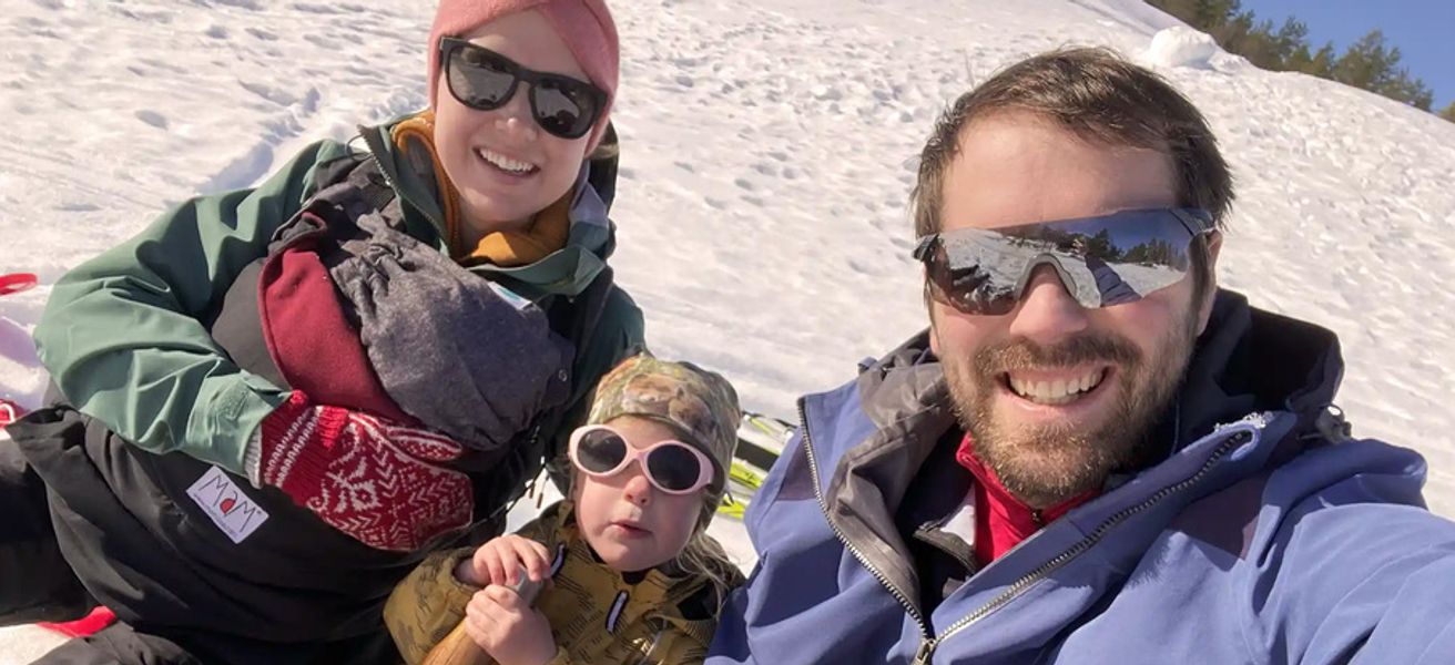 To voksne og to barn ute i snøen med solbriller.
