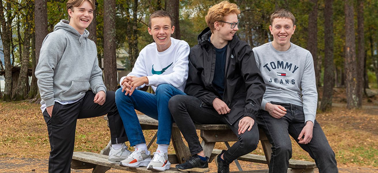 Fire kompiser på 15 år sitter på en benk.