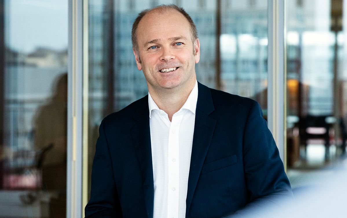 Mann med hvit skjorte og dressjakke, smiler