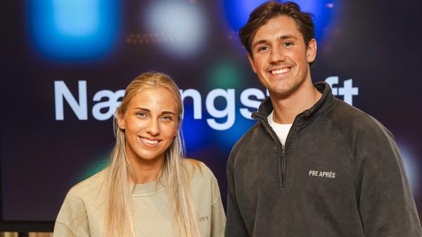 Kvinne og mann som ser i kamera og smiler. Næringsteft står på en skjerm bak.