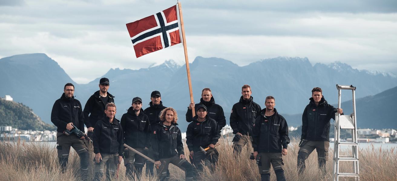 Bilde av ansatte i Snikkergutane som holder et norske flagg
