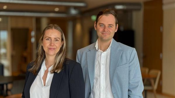 Mann og kvinne i dressjakke og hvit skjorte. Moderne kontorlokaler i bakgrunn