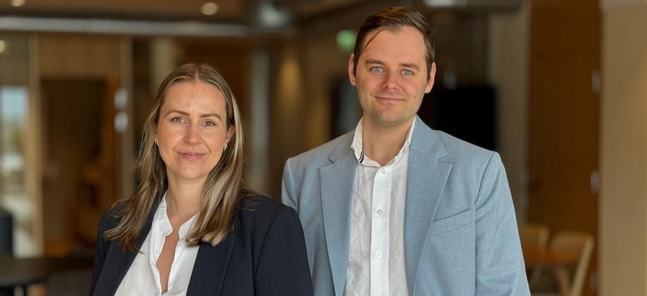Mann og kvinne i dressjakke og hvit skjorte. Moderne kontorlokaler i bakgrunn