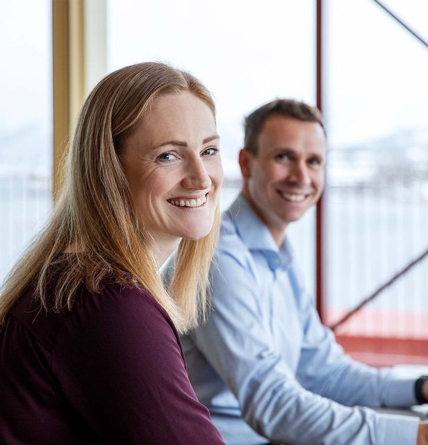 Ung kvinne som er ut av vinduet med kaffi i hånden, moderne leilighet i by.