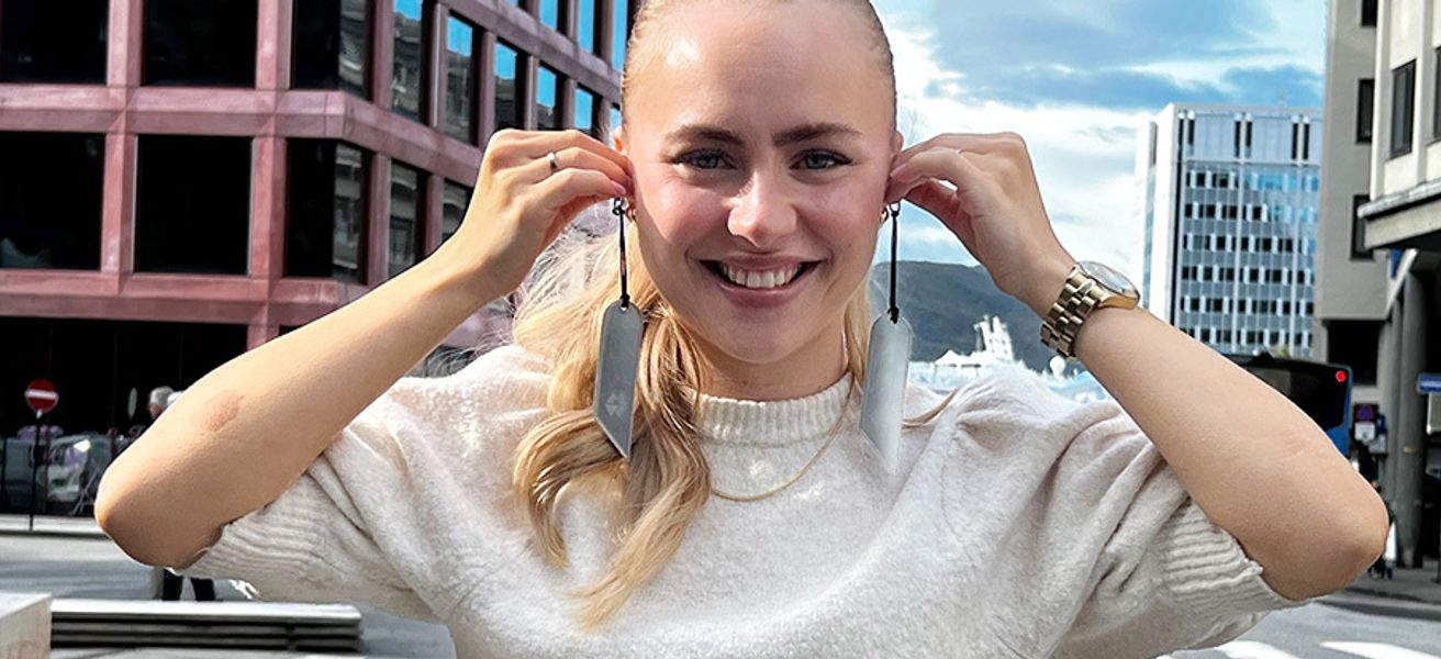 Ung dame som holder to refleks opp til ørene, som om de var øredobber.