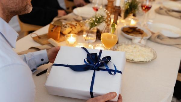 Juledekket bord med en julegave pakket i hvitt papir og blått bånd.