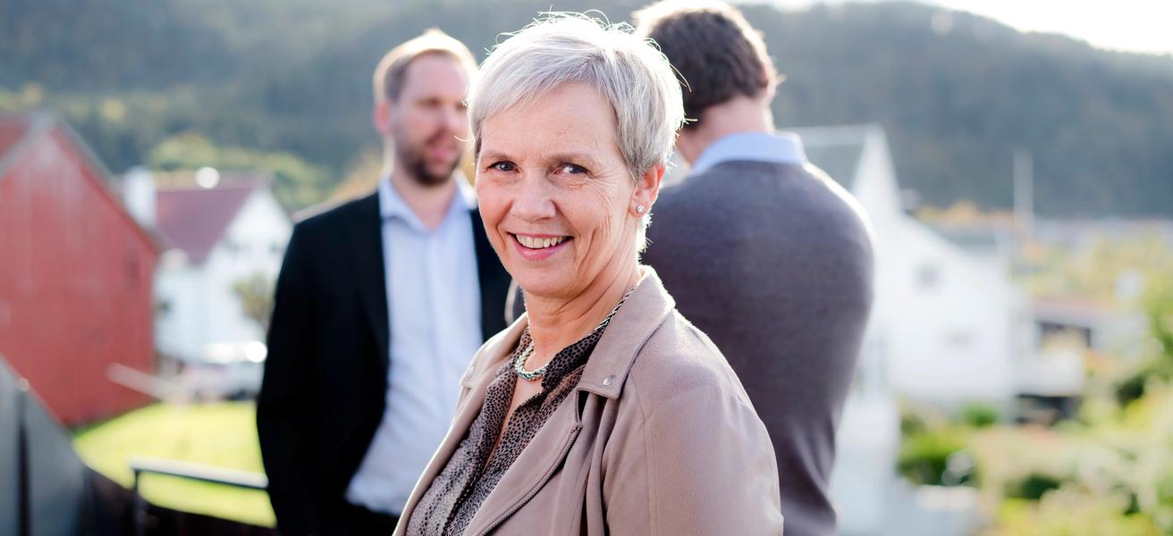 Bilde av kvinne med to menn i bakgrunn.