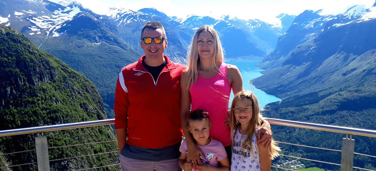 En familie med to voksne og to barn står på en utsiktsplass.