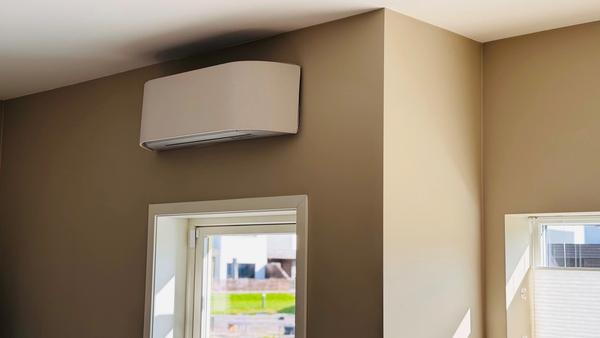 Bilde av en varmepumpe i et hus med beige vegger og solskinn.