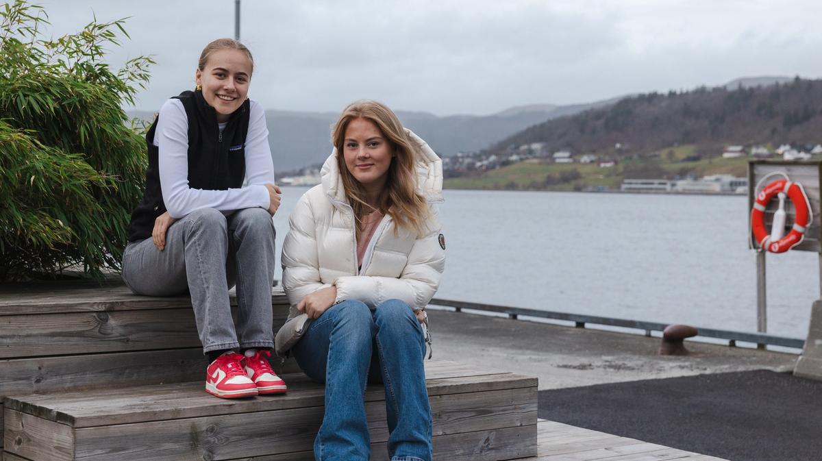 To unge jenter som sitter på en benk ute