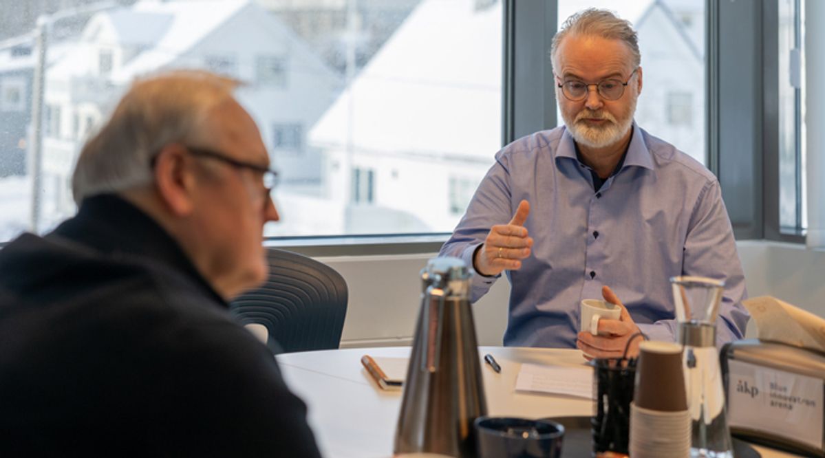 To menn diskuterer over et bord