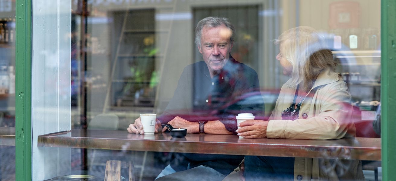 Mann og dame som sitter ved vindusplass på cafe