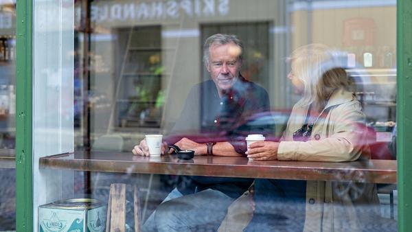 Mann og dame som sitter ved vindusplass på cafe