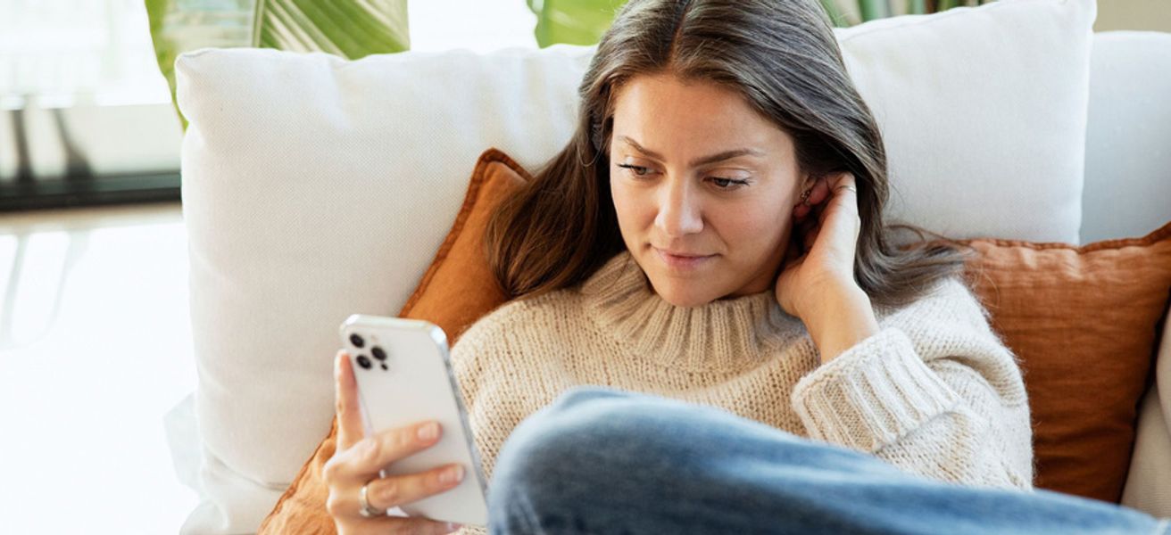 Dame i sofa med mobilen. Rolige omgivelser.