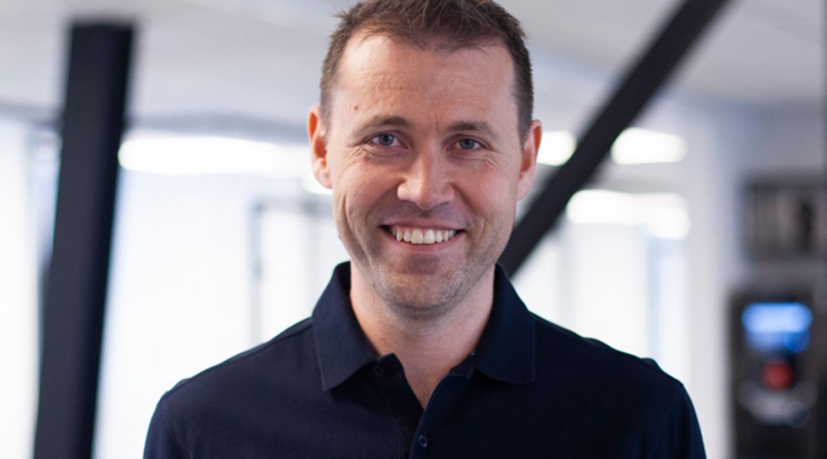 Jan Tore Holen smiler innendørs i moderne kontorlokaler