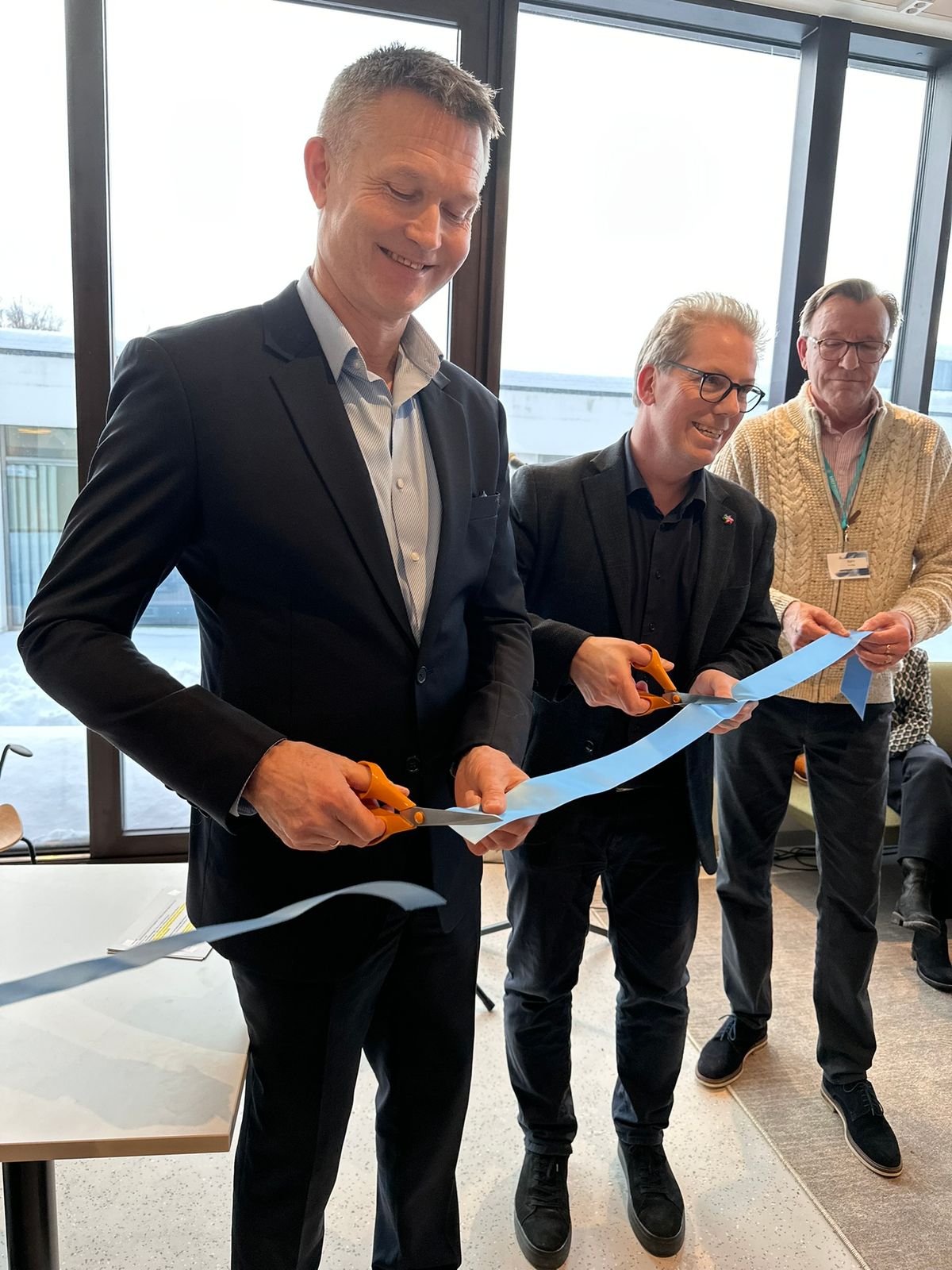 Tre menn som holder en blå snor og klipper den. Offisiell åpning av Vardesenteret.