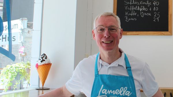 Dirk Kiefer smiler bak disken i iskrembaren Lamella, iført blått forkle med logoen.