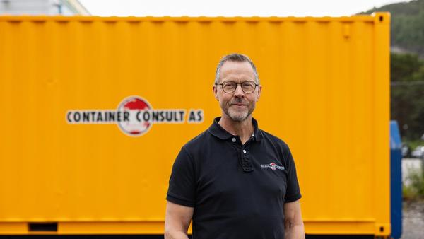Odd Arve Hansen, daglig leder i Container Consult AS, foran gul container med firmalogo.