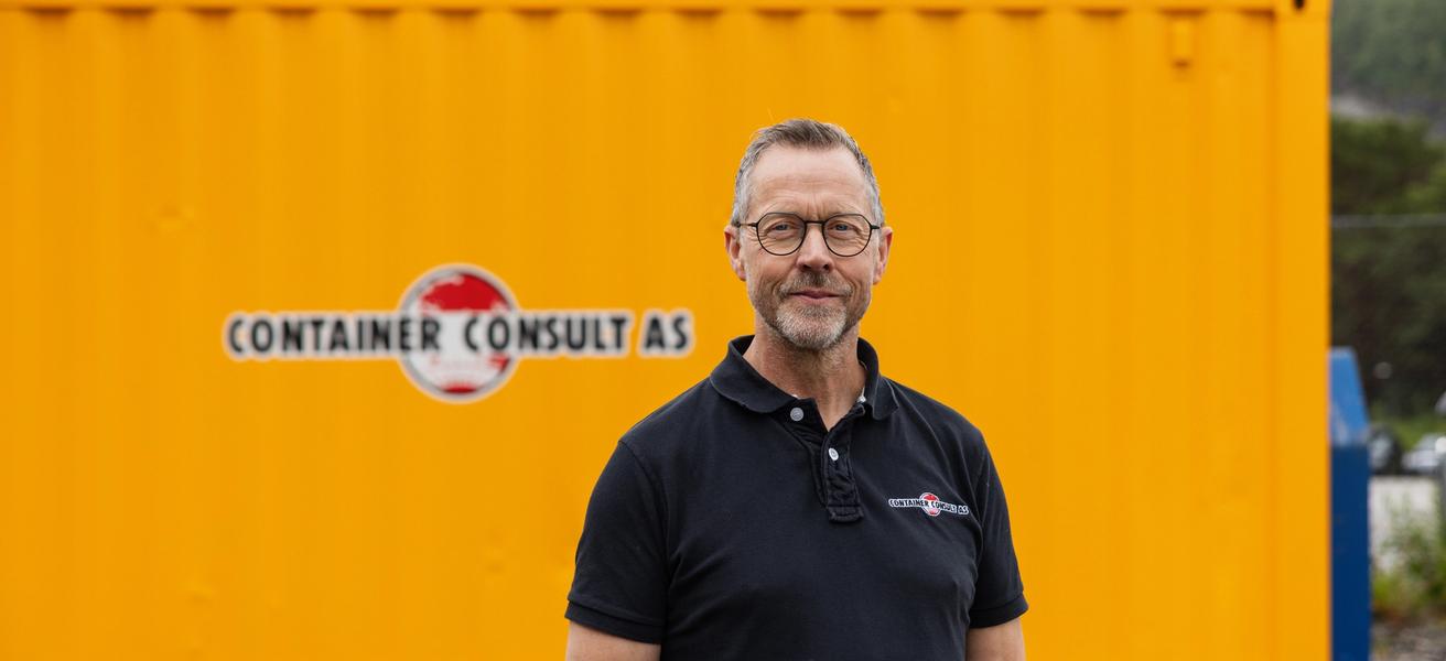 Odd Arve Hansen, daglig leder i Container Consult AS, foran gul container med firmalogo.