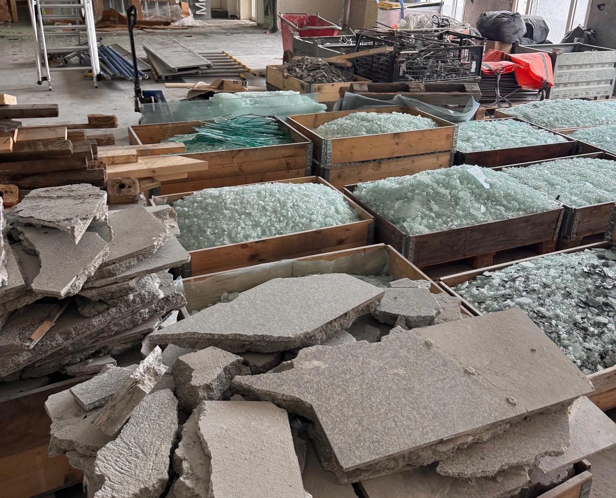 Kasser med knust stein og glass inne i et rehabiliteringsprosjekt.