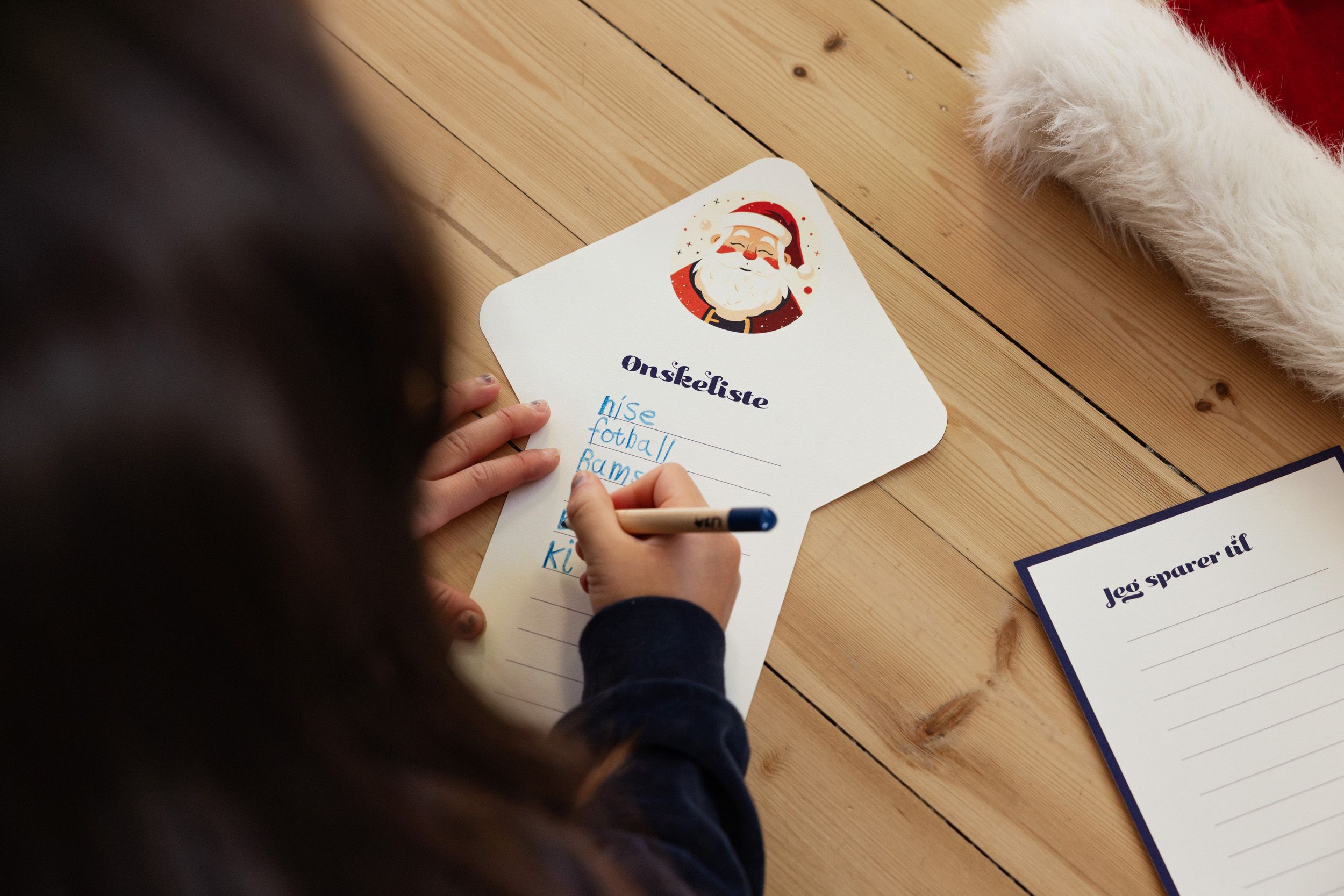 Jente med mørkt hår som skriver ønskeliste til jul 