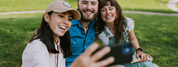 Tre unge personer som tar selfie med mobil
