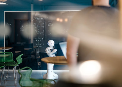 Bilde av en robot fremfor en tavle på et klasserom. 