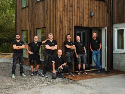 Ansatte i Tingvoll Dør og Vindu utenfor et bygg med trekledning, produsent av skreddersydde dører og vinduer på Nordmøre