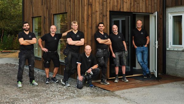 Ansatte i Tingvoll Dør og Vindu utenfor et bygg med trekledning, produsent av skreddersydde dører og vinduer på Nordmøre