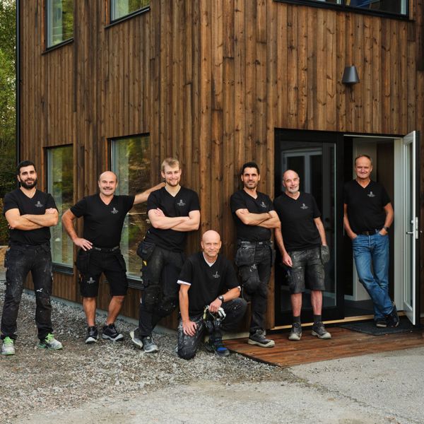 Ansatte i Tingvoll Dør og Vindu utenfor et bygg med trekledning, produsent av skreddersydde dører og vinduer på Nordmøre