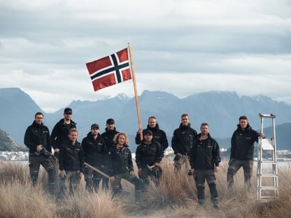 Bilde av ansatte i Snikkergutane som holder et norske flagg