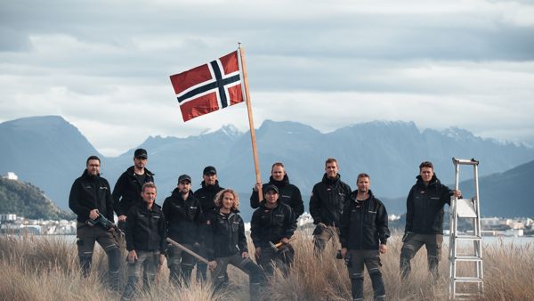 Bilde av ansatte i Snikkergutane som holder et norske flagg