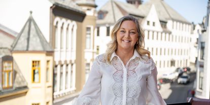 Linda Strømmen, divisjonsleder næringsliv i Sparebanken Møre, stående på en balkong i Ålesund sentrum.