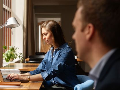 Kvinne sitter ved et skrivebord og skriver på en bærbar PC. 