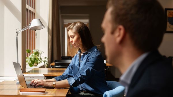 Kvinne sitter ved et skrivebord og skriver på en bærbar PC. 