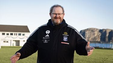 Mann står på en fotballbane. Smiler mot kamera. 