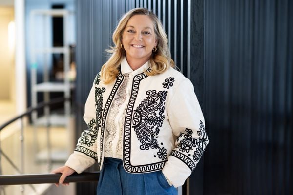 Linda Strømmen leder for næringsliv i Sparebanken Møre står og smiler til kamera med mørk bakgrunn i et moderne lokale
