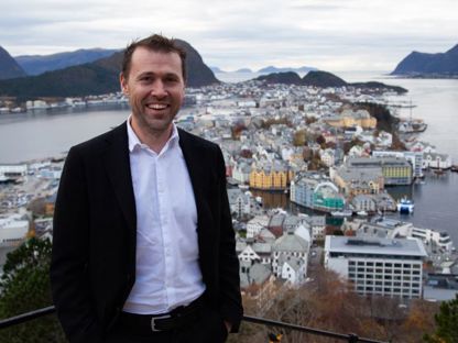 Jan Tore Holen smiler foran utsikt over Ålesunds bysentrum og fjordlandskap