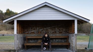 Mann sitter på en innbytterbenk på sidelinjen til en fotballbane.
