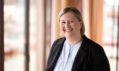 Gunn Eva Aas  smiler til kamera i et morderne lokale, hun har hvit bluse og en svart blazer.