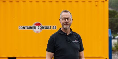 Odd Arve Hansen, daglig leder i Container Consult AS, foran gul container med firmalogo.