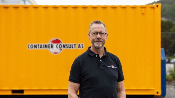 Odd Arve Hansen, daglig leder i Container Consult AS, foran gul container med firmalogo.
