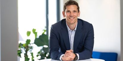 Mann i blå dress smiler til kamera