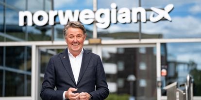 Mann i dress og hvit skjorte står fremfor et forretningsbygg. Norwegian-logo på bygget 