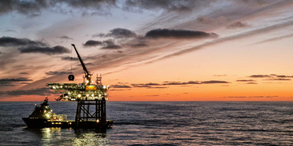 Bilde av plattform og båt ute på havet. Solnedgang 