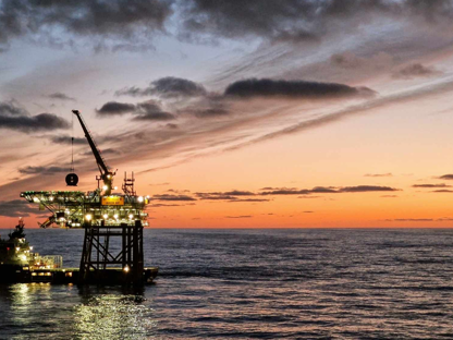 Bilde av plattform og båt ute på havet. Solnedgang 