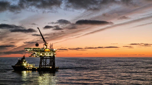Bilde av plattform og båt ute på havet. Solnedgang 