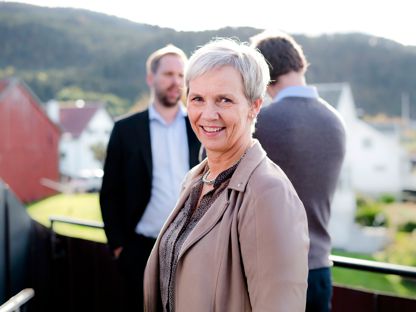 Bilde av kvinne med to menn i bakgrunn. 