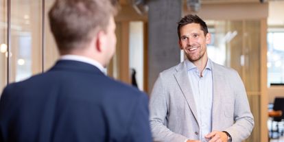 Mann i dress smiler i kamera